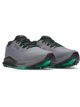 Championes de trail running Under Armour Charged Bandit TR 3, color gris con detalles en negro y verde. Presentan una parte superior de malla técnica para mayor ventilación, refuerzos estratégicos para durabilidad y entresuela Charged Cushioning para máxima amortiguación y respuesta. La suela exterior cuenta con tacos técnicos diseñados para ofrecer una tracción superior en terrenos irregulares.