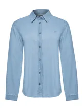 Blusa de denim color celeste, confeccionada en algodón orgánico, con cuello camisero, cierre frontal de botones y manga larga. Presenta un pequeño parche bordado en el pecho.