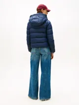 Campera térmica Tommy Hilfiger de corte informal, confeccionada en nailon ligero con relleno de plumón y acabado repelente al agua. Presenta capucha fija con cordón ajustable, cuello levantado, cierre frontal de cremallera y dos bolsillos delanteros con botón a presión. Incluye parche distintivo de la marca en la manga.