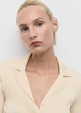 Cardigan de punto fino acanalado en color beige, con cuello en V con solapa, cierre frontal de botones y mangas largas ajustadas.