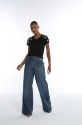 Remera de algodón pima color negro, con escote en V y mangas cortas. Presenta detalles bordados con pedrería en los hombros.