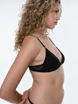 Bralette de encaje color beige con diseño triangular, breteles ajustables y cierre posterior con broche. Cuenta con copas removibles y detalle de pequeño lazo en el centro.