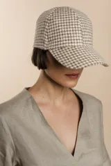 Gorra con visera confeccionada en lana fina sin teñir, con un sutil patrón de tejido en espiga.