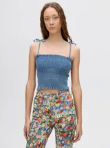 Top crop de tela denim con efecto fruncido, breteles finos ajustables con lazos y diseño entallado al cuerpo.