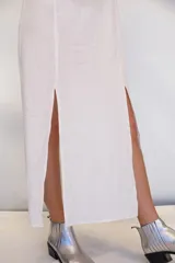 Vestido largo de algodón tusor en color blanco, con volados en las sisas que simulan mangas y aberturas laterales en la falda.