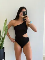 Traje de baño entero negro con un hombro descubierto y abertura en la cintura.