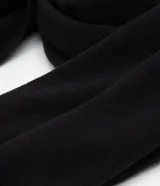 Pañuelo rectangular de color negro, con acabado de mini flecos en los extremos y diseño liso.