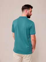 Remera polo blanca de manga corta, con detalles en azul marino en el cuello y los puños, y el logo bordado en el pecho.