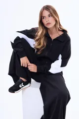 Campera de felpa con cierre frontal, cuello alto y diseño color block en negro y blanco en las mangas. Presenta un corte holgado y puños elásticos.