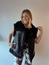 Chaleco negro con forro de peluche, bolsillos delanteros y doble hebilla en el cuello.