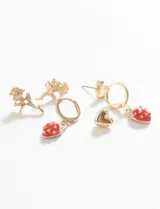 Set de caravanas doradas con tres pares de aros: un par de aros tipo botón con forma de corazón, un par de aros colgantes con forma de rosa y un par de aros tipo argolla con dije de frutilla esmaltada en rojo.