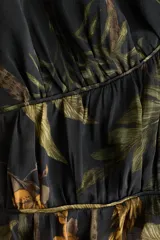 Top corto confeccionado en mezcla de algodón y viscosa, con estampado botánico en tonos verdes y ocres sobre base negra. Presenta escote en V pronunciado, costura elástica fruncida bajo el busto y mangas cortas abullonadas con acabado elástico y volados.