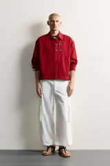 Cazadora relaxed fit de Zara confeccionada en tejido de algodón rojo con efecto lavado. Presenta cuello solapa, manga larga, bolsillos de plastrón en la cadera y cierre frontal de cremallera oculta con solapa y alamares metálicos.