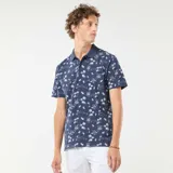 Remera polo azul marino con estampado de palmeras, barcos y paisajes playeros en blanco. De corte clásico y manga corta.