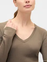 Remera de manga larga con escote en V, confeccionada en tejido de algodón suave y elástico, con un corte ajustado al cuerpo.