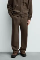 Pantalón jogger de corte regular fit y color negro, confeccionado en tejido compacto de algodón con interior de rizo. Cuenta con cintura elástica, bolsillos frontales y un bolsillo trasero de doble vivo.