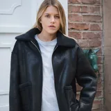 Campera negra de cuero sintético con interior forrado en piel sintética. Tiene cierre frontal y dos bolsillos exteriores abiertos.