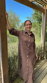 Vestido camisero largo de lino blanco, con cuello camisero, manga corta enrollada y cierre frontal de botones de nácar. Presenta aberturas laterales en el bajo.