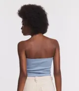 Blusa cropped sin breteles, confeccionada en tejido rib con textura acanalada. Presenta un diseño ajustado y liso.