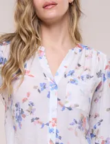 Blusa de gasa Zac & Rachel con estampado de rayas verticales en tonos rosados, amarillos y blancos. Presenta escote en V con cuello mao, cierre frontal con botones, un bolsillo aplicado en el pecho, mangas largas con presilla para regular el largo y detalle de nudo en el dobladillo inferior.