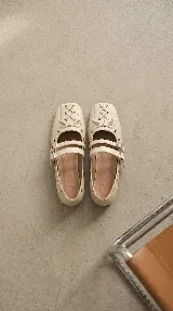 Chatita estilo bailarina color off-white, confeccionada en cuero. Presenta un diseño con doble tira ajustable con hebillas metálicas en el empeine y detalle de cordones cruzados con lazo en la puntera cuadrada. Cuenta con ojales metálicos decorativos en los laterales.