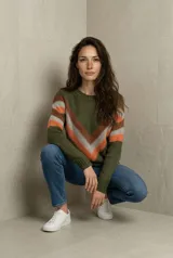 Sweater de tejido tricot con diseño chevron en forma de V en el frente, combinando tonos verde oliva, naranja y gris. Presenta cuello redondo, mangas largas y terminaciones en rib.