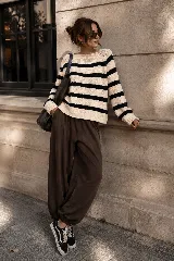 Sweater de punto a rayas horizontales en color crudo y negro, de corte holgado, mangas largas y cuello redondo.