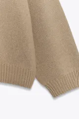 Jersey de punto liso con diseño oversize, cuello redondo y manga larga con puños acanalados.