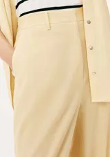 Pantalón de vestir color beige claro, de tiro alto y corte recto ancho, con pinzas frontales y cierre oculto.