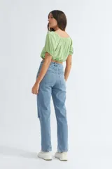 Pantalón de jean celeste, de corte recto, tiro alto y rotura en la rodilla.