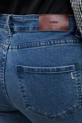 Jean de corte bootcut en color azul medio, con diseño de tiro medio y ruedo deshilachado.