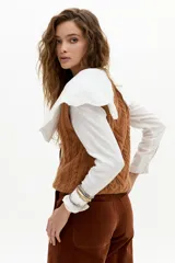 Chaleco de punto color caramelo con ochos en el frente, cuello a la base y terminaciones de rib.