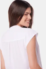 Blusa blanca sin mangas, con cuello mao y cierre frontal oculto con botones.