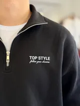 Buzo marrón de felpa con medio cierre y cuello alto, manga larga y puños elásticos. Presenta el texto "TOP STYLE follow your dreams" bordado en el pecho.