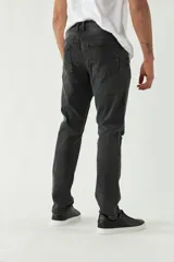 Pantalón de jean azul oscuro con roturas en las rodillas, corte recto y logo bordado en el bolsillo trasero.