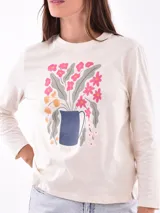 Remera de manga larga color blanco, con cuello redondo y estampa frontal en tono rosado que incluye un diseño de marco con moño y la frase "live simply love sincerely".