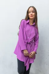 Camisa violeta con textura de plumeti, corte holgado, cuello camisero, cierre frontal con botones y lazo en la cintura.