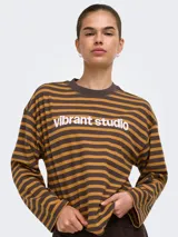 Remera de manga larga a rayas horizontales en tonos marrón y tostado, con cuello redondo y el texto "vibrant studio" estampado en el pecho.
