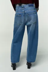 Jeans de tiro medio, color azul claro con efecto lavado y desgaste. Diseño de pernera ancha (barrel) que se estrecha hacia el tobillo. Incluye cinturón fino del mismo tejido.