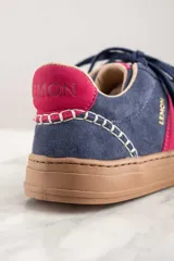 Zapatillas de gamuza azul con detalles en fucsia y suela marrón.