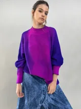 Buzo tejido de lana merino con diseño oversize, manga ranglan y cuello levemente elevado. Presenta un degradado de color vibrante en tonos violeta y fucsia.
