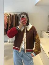 Cardigan de punto con diseño color block, cuello estilo polo en color rosado con borde rojo, cierre frontal con botones, manga derecha en verde oliva y manga izquierda en rojo, con puños y ruedo acanalados a rayas multicolor.