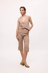 Pantalón capri color beige, de tiro alto y corte recto. Confeccionado en lino y algodón.