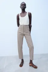 Pantalón de tiro alto con estampado de cuadros vichy en tonos marrón y blanco, con bolsillos laterales de vivo y corte recto.