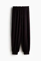 Pantalón globo de corte relajado en punto de crepé, color negro. Cuenta con cintura elástica de tiro bajo con cordón ajustable y piernas globo con puños anchos.