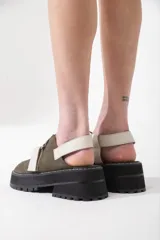 Sandalias de cuero color marrón con tiras cruzadas en blanco y negro, suela track y ajuste con velcro.