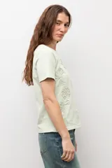 Remera de manga corta color crudo con apliques florales bordados tono sobre tono en el frente.