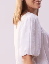 Blusa blanca de gasa marca Zac & Rachel, con frunces en la parte delantera, mangas cortas con puño elastizado, abertura central en la espalda y botón.