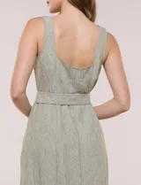 Vestido midi abotonado verde melange, con escote recto, tirantes anchos y falda de calce recto con vuelo sutil. Tiene abotonadura frontal completa con botones estilo carey, cinto textil con hebilla para ajustar la cintura y bolsillos laterales.