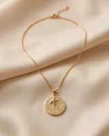 Collar de bronce con cadena fina y dije circular texturizado con una estrella de mar en el centro.